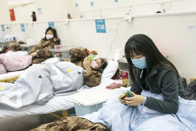 A patient solves a rubik's cube at a temporary hospital converted from “Wuhan Livingroom” in central China's Hubei Province on February 10, 2020. In face of the outbreak of the novel coronavirus pneumonia epidemic, Wuhan authorities have transformed public venues such as exhibition centers and gymnasiums into temporary hospitals. The hospitals have a large capacity of treating patients with mild symptoms and play an important role in isolating the source of infection and cutting off the routes of infection during epidemic prevention. The first batch of patients was hospitalized on Feb. 5. (Photo by Chine Nouvelle/SIPA Press/Rex Features/Shutterstock)