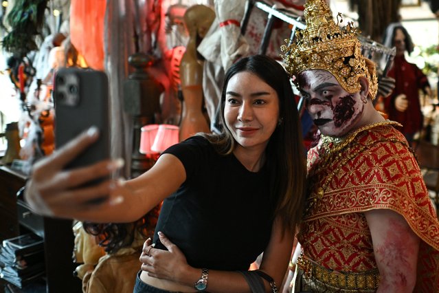 A woman takes a selfie with the a cafe-staff dressed in a halloween costume at a cafe in Bangkok on October 23, 2024. (Photo by Manan Vatsyayana/AFP Photo)