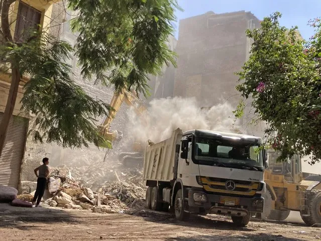 Residents and rescue workers sift through the rubble of a collapsed building in El-Weili neighborhood, Cairo, Egypt, Friday, June 17, 2022. A five-story apartment building collapsed in the Egyptian capital early Friday, killing numerous people according to officials. (Photo by Ahmed Hatem/AP Photo)