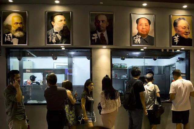 In this photo taken on Saturday, June 25, 2016, customers at a restaurant wait for their orders near the portraits of former Communist leaders including Karl Marx, top left,  and Mao Zedong, second from right at top, in Beijing, China. In a televised speech on the 95th anniversary of the party's formation on July 1, 2016, Chinese President Xi Jinping has urged the 88-million-strong Communist Party to embrace its Marxist roots as he delivered an emphatic call for ideological discipline and a vigorous defense of party rule. (Photo by Ng Han Guan/AP Photo)