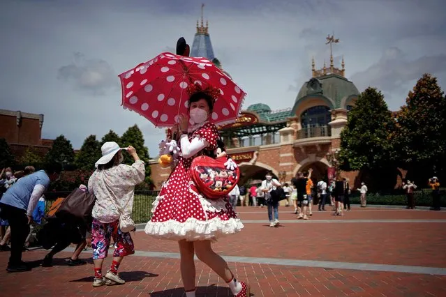 A visitor wearing a face mask poses at the Shanghai Disney Resort, as the Shanghai Disneyland theme park reopens after being shut for the coronavirus disease (COVID-19) outbreak, in Shanghai, China on June 30, 2022. (Photo by Aly Song/Reuters)