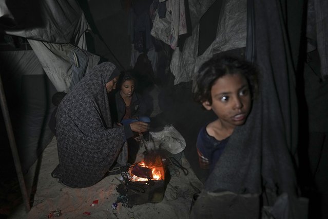Shireen Daifallah, who was displaced with her children from northern Gaza, checks the fire next to their tent at a camp for displaced people in Deir al-Balah. Gaza Strip, Saturday, November 30, 2024. (Photo by Abdel Kareem Hana/AP Photo)