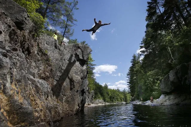 Russell Keene, 52, of Livermore Falls, Maine, does a swan dive into the Swift River off a cliff at Coos Canyon in Byron, Maine. The canyon is considered one of the premier swimming holes in the U.S. (Photo by Robert F. Bukaty/AP Photo)