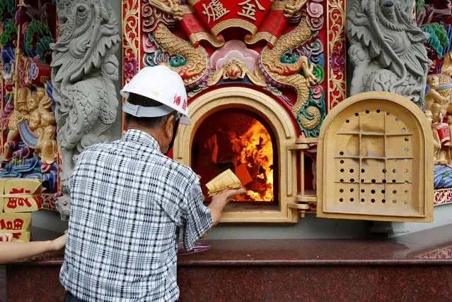 Lin Fu-chun, CEO of Chuanso factory, that manufactures temples and other religious objects, burns Chinese paper offerings used to pay respects to the deceased and gods, in Pingtung, Taiwan July 5, 2016. (Photo by Tyrone Siu/Reuters)