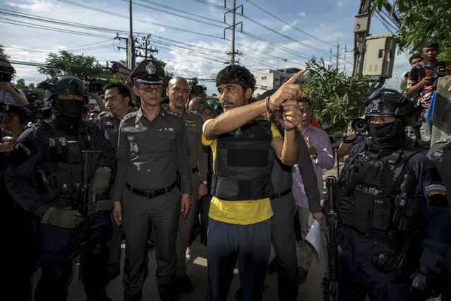 A suspect of the August 17 Bangkok blast who was arrested last week near the border with Cambodia points as he stands next to police officers during a crime re-enactment at an apartment, where police raided and found possible bomb-making materials last month, in Nongjok district, on the outskirts of Bangkok, Thailand, September 8, 2015. (Photo by Athit Perawongmetha/Reuters)