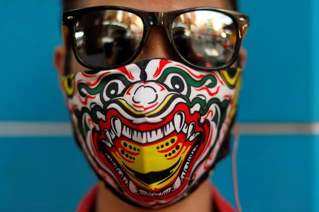 A street vendor wearing a protective face mask depicting traditional Thai theatre dancer poses for a picture, after the government started opening some restaurants outside shopping malls, parks, and barbershops during the coronavirus disease (COVID-19) outbreak in Bangkok, Thailand, May 3, 2020. (Photo by Jorge Silva/Reuters)