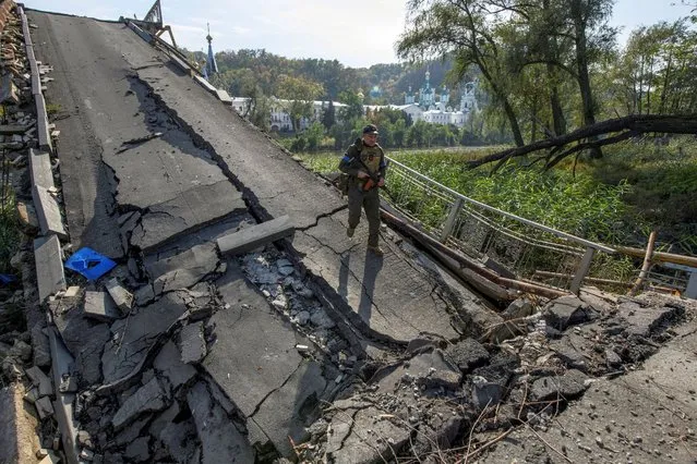 A service member of Ukraine's National Guard walks on a bridge over the Siverskyi Donets river destroyed during Russia's attack on Ukraine, in the town of Sviatohirsk, Donetsk region, Ukraine on October 1, 2022. (Photo by Vladyslav Musiienko/Reuters)