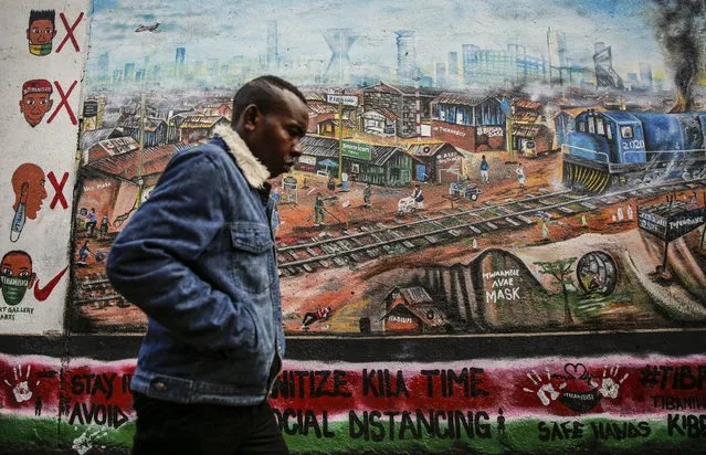 A man walks past an informational mural with messages in English and Swahili warning people about the dangers of the new coronavirus and how to prevent transmission, painted by youth artists from the Uweza Foundation, in the Kibera slum, or informal settlement, of Nairobi, Kenya Wednesday, July 8, 2020. Africa now has more than a half-million confirmed coronavirus cases, according to the Africa Centers for Disease Control and Prevention, but the true number of cases among Africa's 1.3 billion people is unknown as its 54 countries face a serious shortage of testing materials for the virus. (Photo by Brian Inganga/AP Photo)