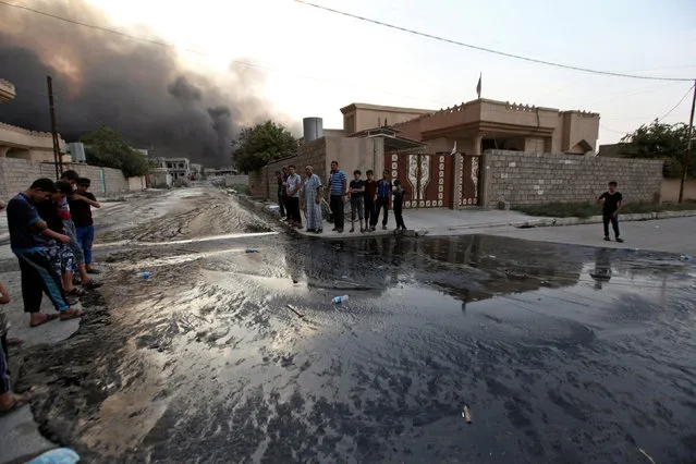 Residents look at oil spill from wells, set ablaze by Islamic State militants before fleeing the oil-producing region of Qayyara, in Qayyara, Iraq, August 29, 2016. (Photo by Azad Lashkari/Reuters)