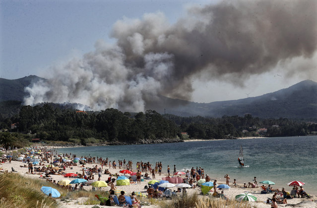 Smoke rises from the forest fire originated next to a touristic beach in Porto de Son, A Coruna, northern Spain, 21 July 2020. (Photo by Lavandeira Jr./EPA/EFE)