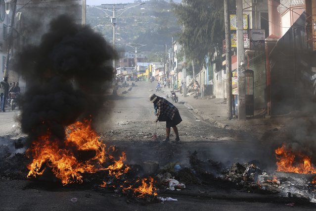 A woman sweeps debris next to a blazing barricade set up by demonstrators during a protest against insecurity in Port-au-Prince, Haiti, Wednesday, April 2, 2025. (Photo by Odelyn Joseph/AP Photo)