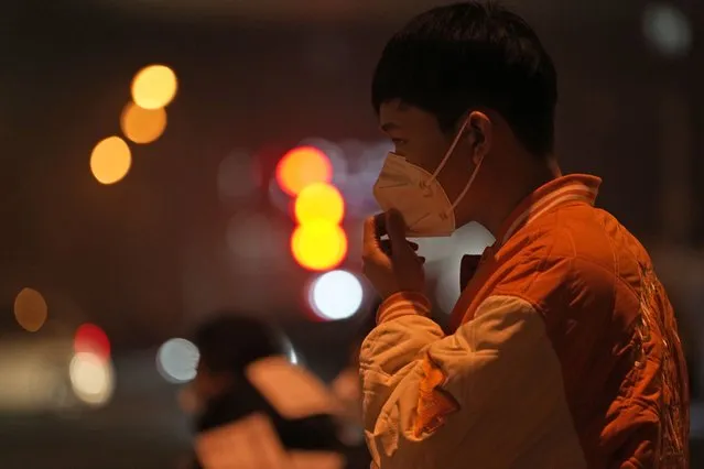 A man adjusts his mask on the street of Beijing, Sunday, November 20, 2022. China on Sunday announced its first new death from COVID-19 in nearly half a year as strict new measures are imposed in Beijing and across the country to ward against new outbreaks. (Photo by Ng Han Guan/AP Photo)