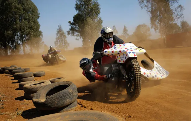 A sidecar racers hangs off the side of the sidecar motorbike as his friend rides the bike around the Walkerville Dirt Oval south of Johannesburg, South Africa, 06 August 2016. Sidecar racing is very dangerous as the “passenger” needs to hang off the bike to keep it stable. The bikes have 1000cc motors and with only a hand full of racers is a very rare form of motorsport. (Photo by Kim Ludbrook/EPA)