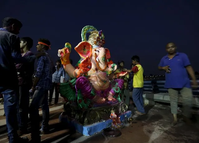 Devotees stand around an idol of the Hindu god Ganesh, the deity of prosperity, before its immersion during the ten-day-long Ganesh Chaturthi festival in Ahmedabad, India, September 23, 2015. (Photo by Amit Dave/Reuters)