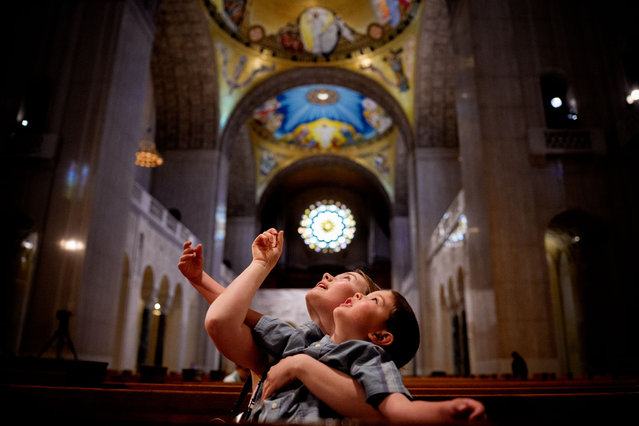Caretaker Ellie Gifford, visiting from Cincinnati, Ohio, holds Joseph Mathews, 4, in her arms as they look up at the ceiling of the Basilica of the National Shrine of the Immaculate Conception in the wake of the the death of Pope Francis on April 21, 2025 in Washington, DC. The Vatican announced that Pope Francis, 88, died on Monday at 07:35 local time and "the Bishop of Rome, Francis, returned to the home of the Father". His death comes after he appeared in St Peter's Square on Easter Sunday, greeting thousands of worshippers. (Photo by Andrew Harnik/Getty Images)