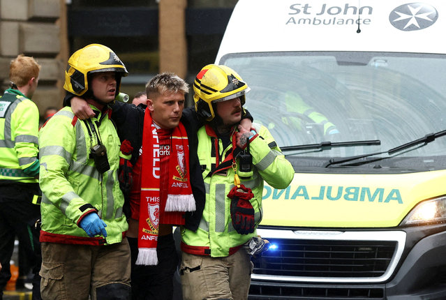 A fan is assisted by fire fighters at an incident after a car ploughed into a crowd of Liverpool fans during a Premier League title parade in Liverpool, Britain on May 26, 2025. (Photo by Lee Smith/Action Images via Reuters)