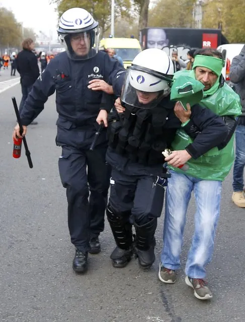 An injured  policeman is helped during clashes with demonstrators in central Brussels November 6, 2014. (Photo by Yves Herman/Reuters)