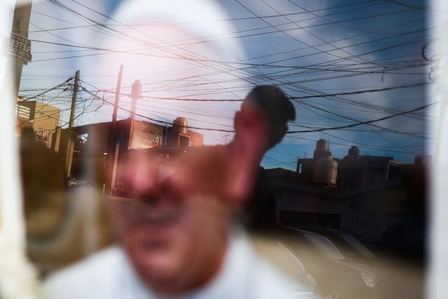 A person is reflected in a picture of Pope Francis placed outside the Virgen de Caacupe chapel, following the death of the pontiff, in Buenos Aires, Argentina, on April 21, 2025. (Photo by Matias Baglietto/Reuters)