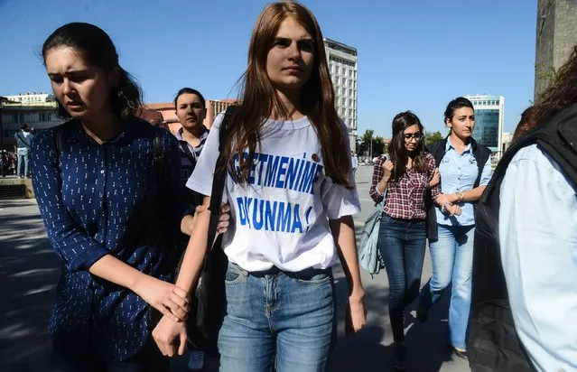 Turkish police detain a student wearing a t-shirt reading “Don't touch my teacher!” in Diyarbakir on September 19, 2016, during a protest against the suspension of teachers for suspected links to militants. Turkey on September 8, 2016 suspended teachers suspected by the education ministry of having engaged in activities in support of the outlawed Kurdistan Workers' Party (PKK) listed as a terror group by Ankara and its Western allies. Turkish schools reopened September 19 for the first time since the July 15 coup following a summer which saw tens of thousands of teachers sacked or suspended over “links” to the plotters or to Kurdish rebels. (Photo by Ilyas Akengin/AFP Photo)