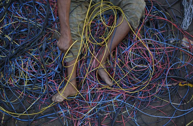 A man removes copper wiring from electrical cables outside a scrap shop in Dharavi, one of Asia's largest slums, in Mumbai December 10, 2012. (Photo by Danish Siddiqui/Reuters)