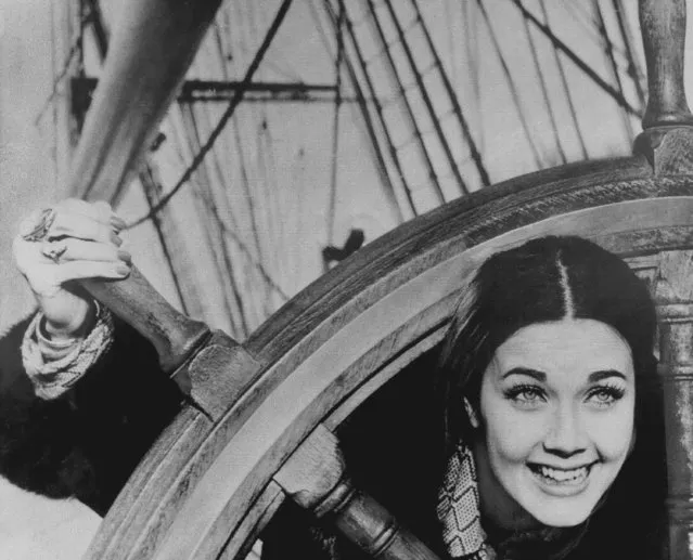 Miss USA, Lynda Carter, 21, of Tempe, Ariz., plays peek-a-boo through the steering wheel of the ancient sailing clipper, “Cutty Sark”, which she and other Miss World contestants visited at nearby Greenwich of London, Nov. 23, 1972. (Photo by AP Photo)
