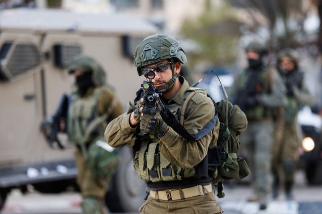 An Israeli soldier aims a weapon as they take position during a raid, in Ramallah, in the Israeli-occupied West Bank on March 4, 2024. (Photo by Mohammed Torokman/Reuters)