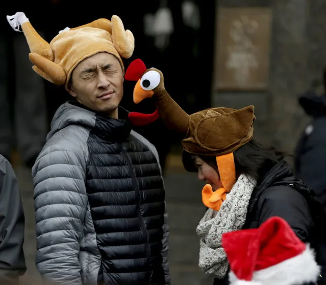 Tamari Hedani, right, hits her boyfriend, Chris Chu, both from San Francisco, with her turkey hat prior to the start of the Macy's Thanksgiving Day Parade, Thursday, November 27, 2014, in New York. (Photo by Julio Cortez/AP Photo)