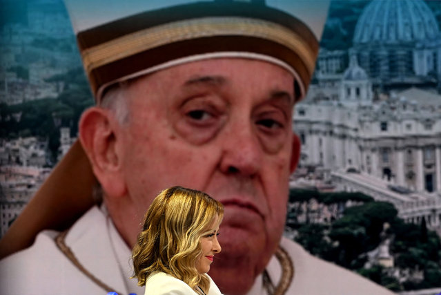 Italy's Prime Minister Giorgia Meloni smiles by a picture of Pope Francis as she attends Italian National TV show “Porta a Porta” in Rome on April 4, 2024. (Photo by Filippo Monteforte/AFP Photo)