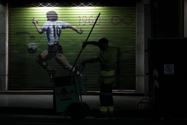 A garbage worker cleans the sidewalk by a mural of late soccer star Diego Maradona in Buenos Aires, Argentina, early Monday, March 10, 2025. (Photo by Natacha Pisarenko/AP Photo)