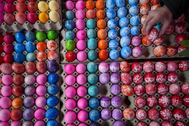 A vendor shows hand decorated Easter eggs, on Orthodox Good Friday at a green market in Belgrade, Serbia, Friday, May 3, 2024. (Photo by Darko Vojinovic/AP Photo)