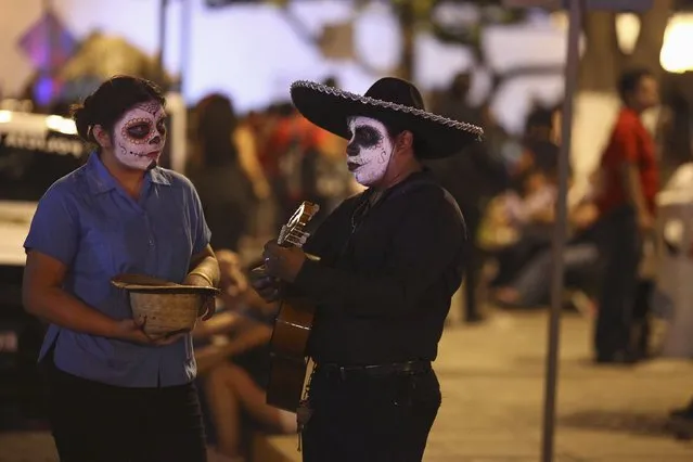 A street musician and his aide, both with calavera face paint for Day of the Dead celebration, perform in Merida, Mexico, October 31, 2015. (Photo by Lorenzo Hernandez/Reuters)