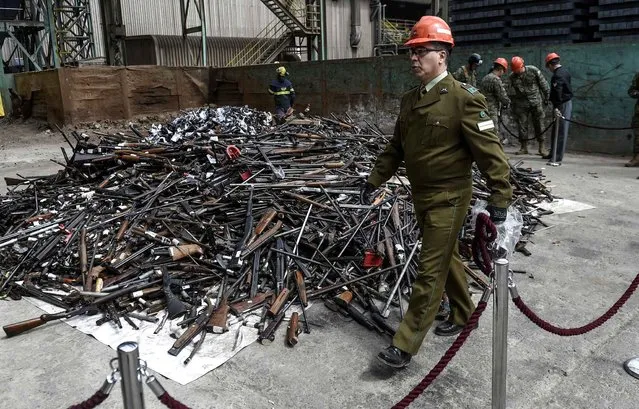 Chilean soldiers and policeman guard next to some 14000 weapons which wait to be destroyed in Santiago on October 6, 2016. (Photo by Martin Bernetti/AFP Photo)