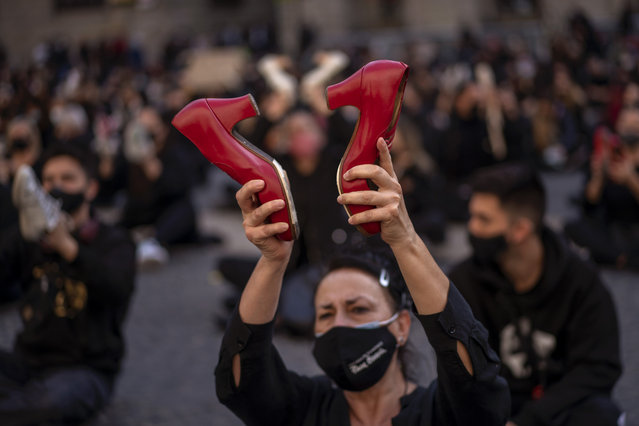 A flamenco dancer holds up her dancing shoes during a protest organised by dance associations against virus restrictions, in Barcelona, Monday, November 9, 2020, as Spain continue with new measures to try to prevent the spread of COVID-19. (Photo by Emilio Morenatti/AP Photo)