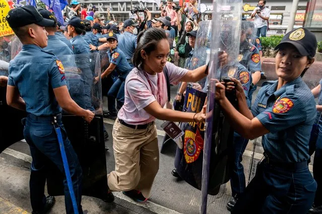 A woman attempts to get past a police blockade during a protest on Women's Day, in Manila, Philippines on March 8, 2023. (Photo by Lisa Marie David/Reuters)
