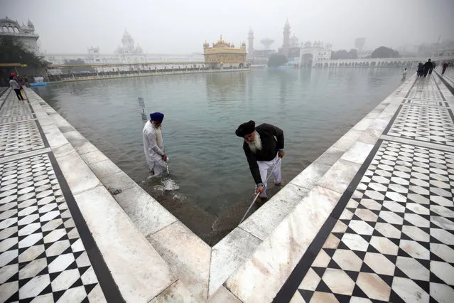 Sikh men perform the service of cleaning the “Sarowar” or the sacred pond of the Golden Temple, the holiest of Sikh shrines on the occasion of the 349th birth anniversary of the tenth Guru or master of the Sikhs, Sri Guru Gobind Singh in Amritsar, India, December 28, 2014. Guru Gobind Singh Ji was the Guru who initiated the special order or sect of the Sikhs called the Khalsa Panth. (Photo by Raminder Pal Singh/EPA)