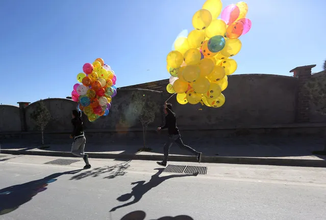 Afghan boys run as they hopes to sell colored balloons on a street in Kabul, Afghanistan, Monday, November 16, 2015. (Photo by Rahmat Gul/AP Photo)