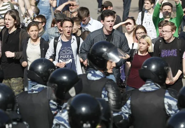 Protesters shout anti-government slogans behind a police line at a demonstration against President Vladimir Putin in Pushkin Square in Moscow, Russia, Saturday, May 5, 2018. A group that monitors political repression in Russia says more than 350 people have been arrested in a day of nationwide protests against the upcoming inauguration of Vladimir Putin for a new six-year term as president. (Photo by Pavel Golovkin/AP Photo)