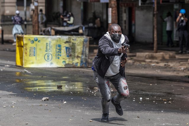 A plain-clothed policeman charges at protesters brandishing his pistol during an anti-government demonstration called following nationwide deadly protests over tax hikes and a controversial now-withdrawn tax bill in downtown Nairobi, on July 2, 2024. Kenyan police fired tear gas to scatter small crowds in the capital Nairobi on Tuesday, AFP reporters saw, after youth activists called for fresh protests following deadly violence during anti-tax hike demonstrations last month. Activists have stepped up their campaign against President William Ruto despite his announcement last week that he would not sign into law a controversial finance bill that triggered what he has branded “treasonous” protests. (Photo by Tony Karumba/AFP Photo)