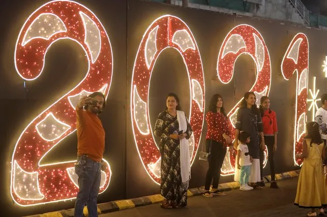 People pose for a picture next to an installation at a mall on New Year's Eve in Mumbai, India, December 31, 2020. (Photo by Francis Mascarenhas/Reuters)