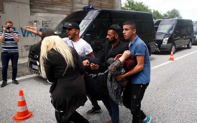 People help a migrant who got sick after her bus was stopped and turned back by the police, near Konjic, Bosnia and Herzegovina May 18, 2018. (Photo by Dado Ruvic/Reuters)