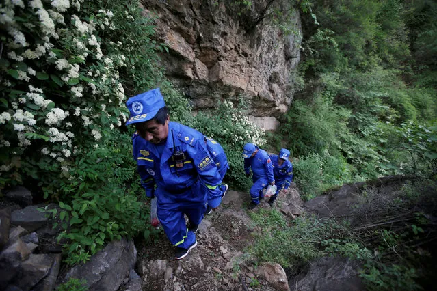 Rescuers climb along a path to their service point for the Great Wall Marathon in Jixian of Tianjin, China May 19, 2018. (Photo by Jason Lee/Reuters)