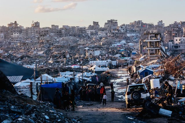 Displaced palestinians stand on a road after heavy rain in Jabalia city, northern Gaza Strip, on November 25, 2025. The Gaza Strip has been largely reduced to rubble after two years of fighting, sparked by Hamas's attack on Israel on October 7, 2023, which resulted in the deaths of 1,221 people. Israel's retaliatory assault on Gaza has killed at least 69,733 people, according to figures from the health ministry that the UN considers reliable. (Photo by Omar Al-Qattaa/AFP Photo)