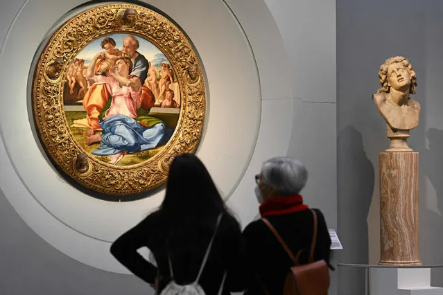 Visitors view Michelangelo's 1505-1507 “Holy Family with the Young St. John the Baptist” (L), known as the “Doni Tondo” on January 21, 2021 on the reopening of the Uffizi Galleries in Florence, Tuscany. The Uffizi Galleries in Florence, a museum famous for its collection of Italian Renaissance masterpieces, reopens on January 21, 2021 under tight security after months of forced closure due to the Covid-19 pandemic. (Photo by Vincenzo Pinto/AFP Photo)