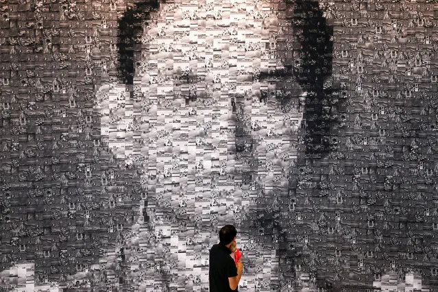 A man carries an infant as he walks past a collage of pictures of Thailand's late King Bhumibol Adulyadej during an exhibition held in his honour at Bangkok Art and Culture Centre (BACC) in Bangkok, Thailand, November 4, 2016. (Photo by Athit Perawongmetha/Reuters)