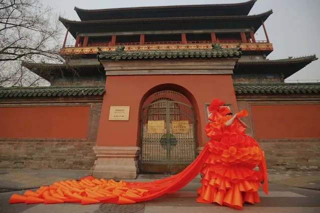 Chinese artist Kong Ning symbolically makes warning sounds in her costume made of hundreds of orange plastic blowing horns during her art performance raising awareness of the hazardous smog in front of the Drum tower in a historical part of Beijing on a very polluted day December 7, 2015. (Photo by Damir Sagolj/Reuters)