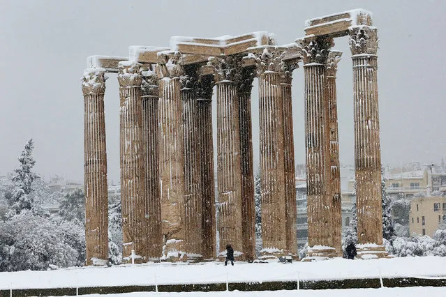Employees make their way in the archaeological site of the Temple of Zeus during heavy snowfall, in Athens, Greece, 16 February 2021. As the cold front Medea sweeping over Greece was in full progress and heading south, very low temperatures were recorded in the northern parts of the country. (Photo by Orestis Panagiotou/EPA/EFE)
