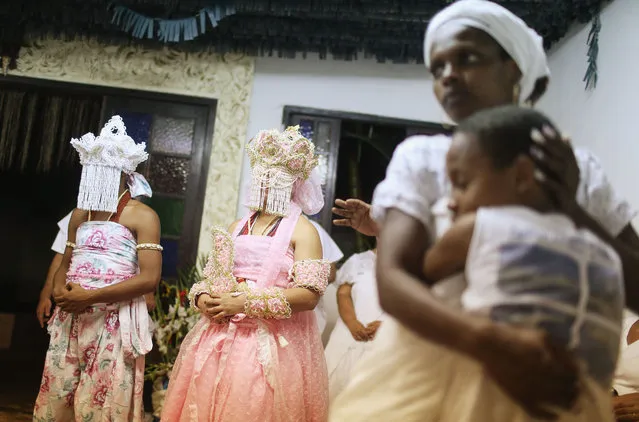 Worshippers gather, some dressed as female deities (L), during a Candomble ceremony honoring goddesses Iemanja and Oxum on December 13, 2015 in Itaborai, Brazil. Candomble is an Afro-Brazilian religion whose practitioners sometimes fall into trances during ceremonies believing they have become possessed by gods, or orixas. (Photo by Mario Tama/Getty Images)