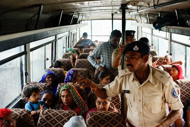 People sit in a bus during an evacuation as a police officer does a headcount before the arrival of cyclone Biparjoy in Jakhau, in the western state of Gujarat, in Jakhau, India on June 14, 2023. (Photo by Francis Mascarenhas/Reuters)