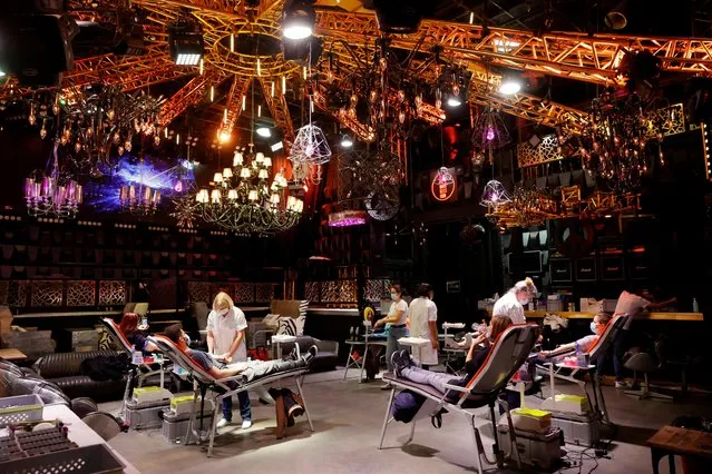 People give blood on the stage of the closed MAD (Moulin a Danse) night club during the outbreak of the coronavirus disease (COVID-19) in Lausanne, Switzerland, December 7, 2020. (Photo by Denis Balibouse/Reuters)
