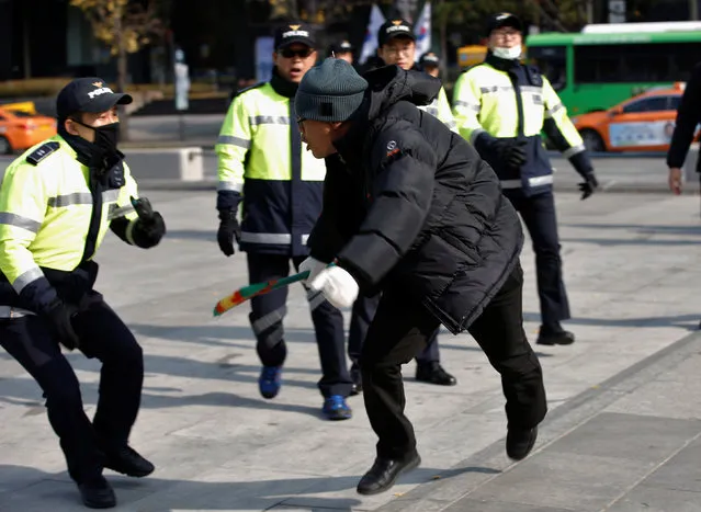 A protester, participating in a “cleaning the road around the presidential Blue House” activity criticizing South Korean President Park Geun-hye, runs to avoid policemen who try to stop him while protesters make their way towards the presidential Blue House in central Seoul, South Korea, November 16, 2016. (Photo by Kim Kyung-Hoon/Reuters)
